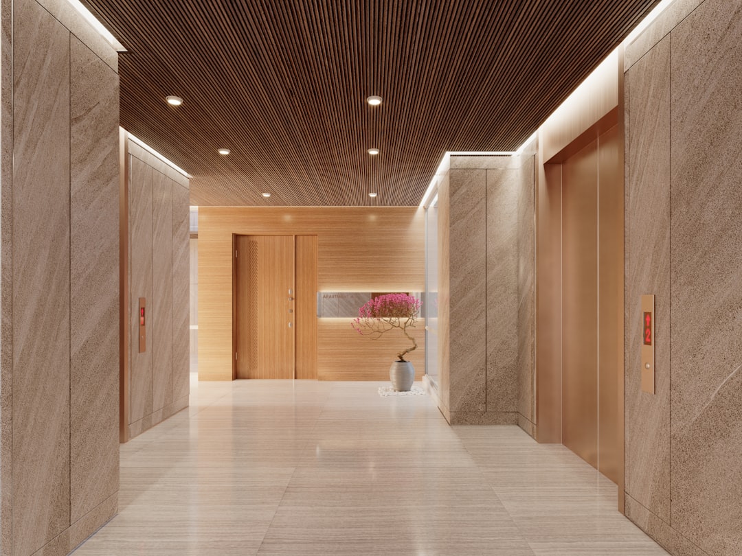 Elegant Modern Elevator Lobby with Marble Walls, Wooden Accents, Soft Lighting, and Stylish Floral Decoration for a Luxurious Residential Building.