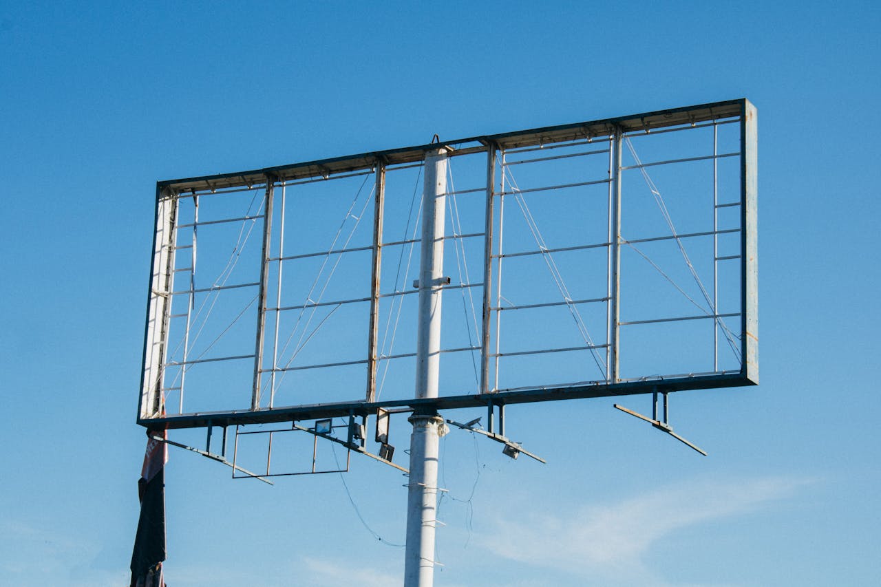 Empty metal billboard frame standing against a clear blue sky, highlighting outdoor advertising infrastructure.